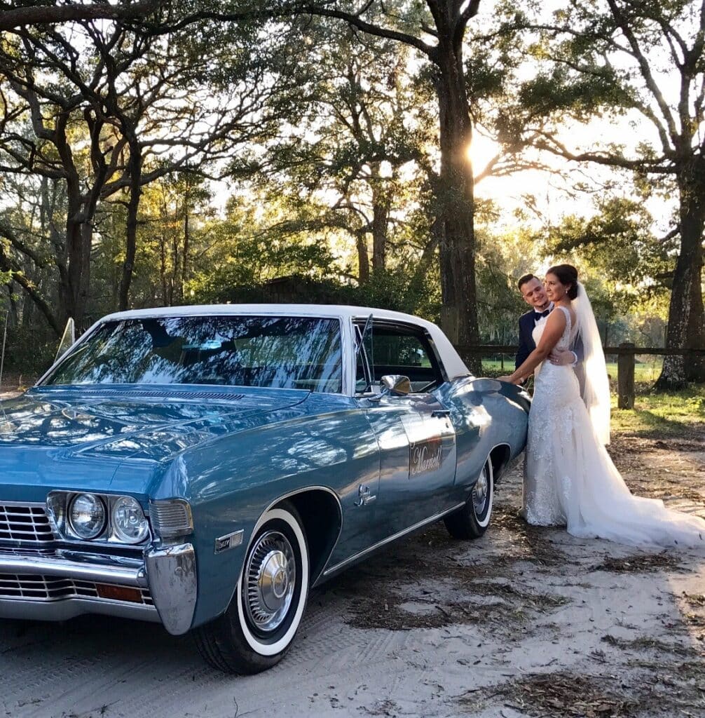 Bride and groom stand by the classic car 1968 Chevy Impala.