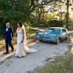 Bride and groom walk in front of the 68 Impala.