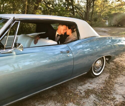 Bride and groom sitting in the classic 68 Chevy Impala.