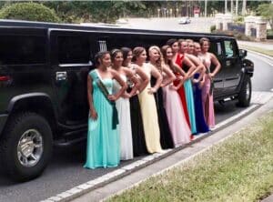 High school girls standing beside the Hummer limo before prom.
