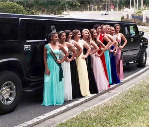 High school girls standing beside the Hummer limo before prom.