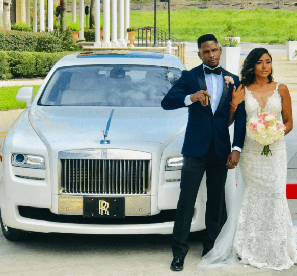 Bride and groom posing with the Rolls Royce Ghost
