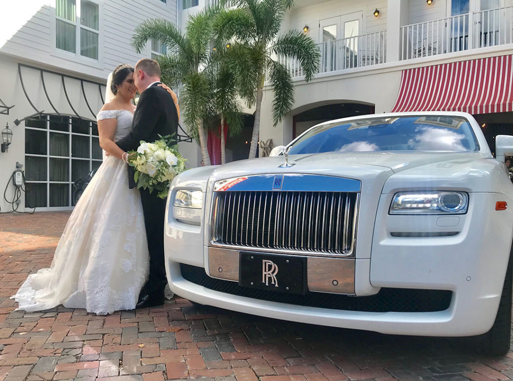 Bride and groom stand next to the white Rolls Royce Ghost