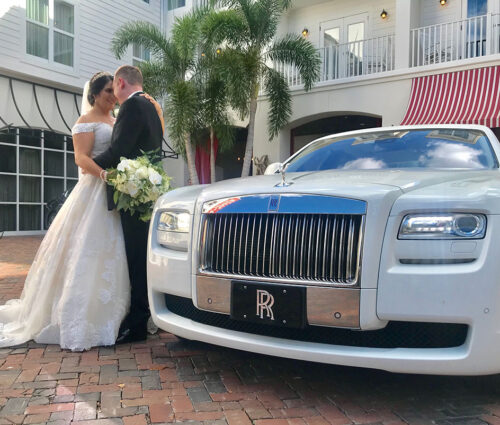 Bride and groom stand next to the white Rolls Royce Ghost