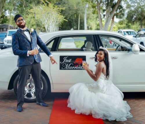 Bride and groom pose in front of Exotic Limo's Rolls Royce Ghost.
