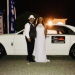 Bride and groom standing by Rolls Royce with custom "just married" sign.