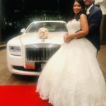 Bride and groom post on the red carpet in front of their wedding limo, the Rolls Royce Ghost