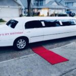 Exotic Limo's white Lincoln limousine with red carpet and birthday sign.