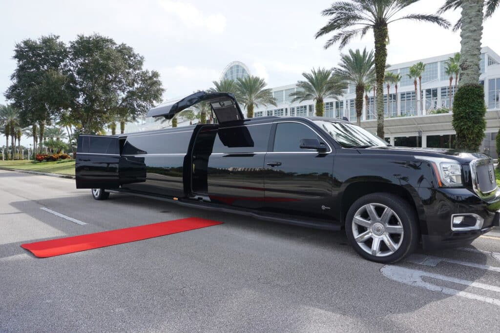 Black Cadillac Escalade Limo with doors open and red carpet.