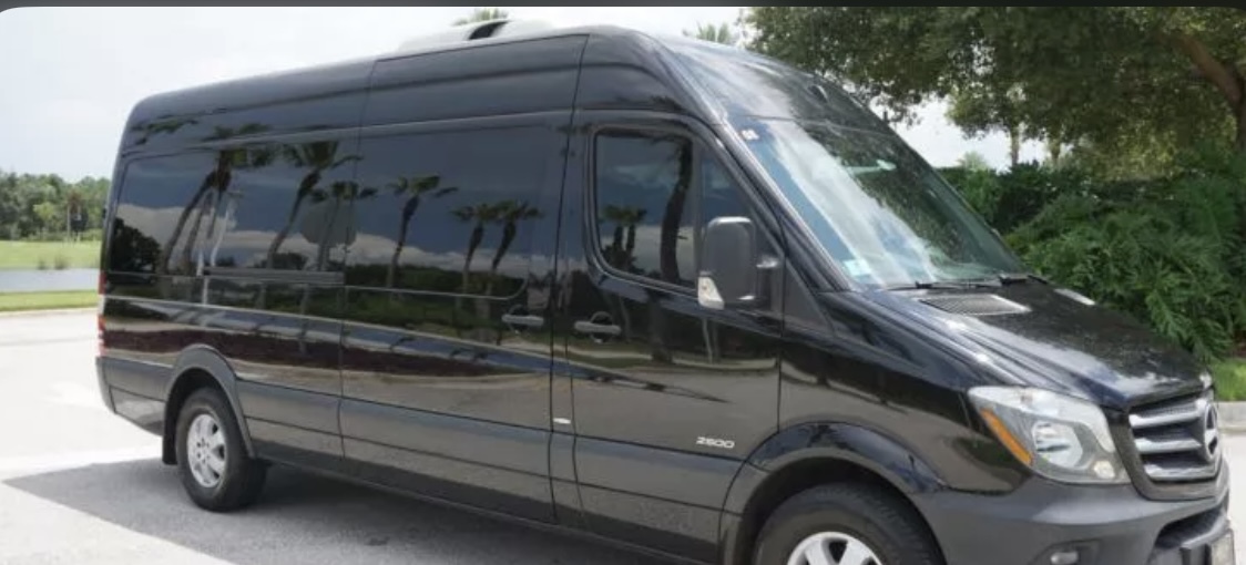A sleek black Mercedes Sprinter van, spacious enough to accommodate 14 passengers, parked outdoors. The Mercedes passenger van belongs to the Exotic Limo Orlando vehicle fleet. 