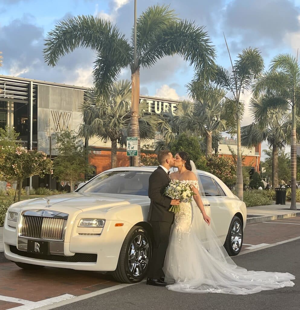 Bride and groom kiss next to the Rolls Royce Ghost
