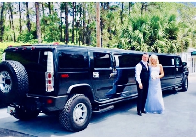 Bride and groom stand beside the 18-passenger Hummer limo.